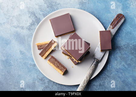 Schokolade Karamell Schichten, Bars, Millionäre shortbread auf einem Teller. Blauen Hintergrund. Ansicht von oben. Stockfoto