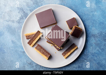 Schokolade Karamell Schichten, Bars, Millionäre shortbread auf einem Teller. Blauen Hintergrund. Ansicht von oben. Stockfoto