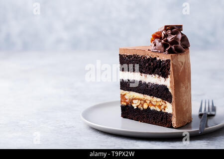 Schokolade, Karamell, Erdnuß-Kuchen, Snickers auf einem Teller. Grauer Hintergrund. Kopieren Sie Platz. Stockfoto