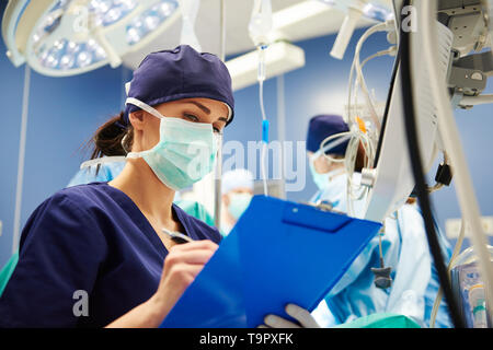 Weibliche Krankenschwester Prüfung aller Parameter im Operationssaal Stockfoto