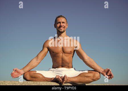 Yoga hilft Balance zu finden und mit der Natur zu vereinen. Yoga hilft, Harmonie und Gleichgewicht zu finden. Mann, Yoga und blauer Himmel. Erreicht Frieden des Stockfoto