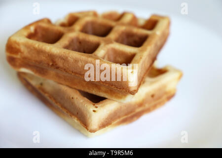 Belgische Waffeln in einer weißen Platte. Gesundes Frühstück, Stücke von frisch gebackenem classic Wafer, Kalorien essen Stockfoto