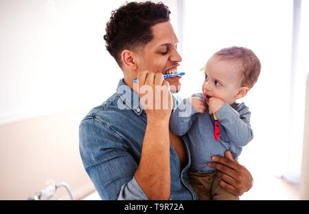 Vater und Sohn in einer kleinen toddler Badezimmer zuhause zu Hause, die Zähne putzen. Stockfoto