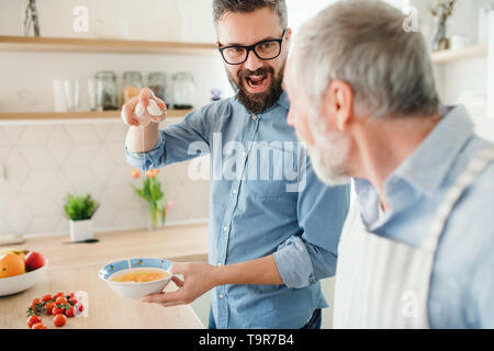 Ein erwachsener hipster Sohn und Vater in Innenräumen zu Hause, kochen. Stockfoto