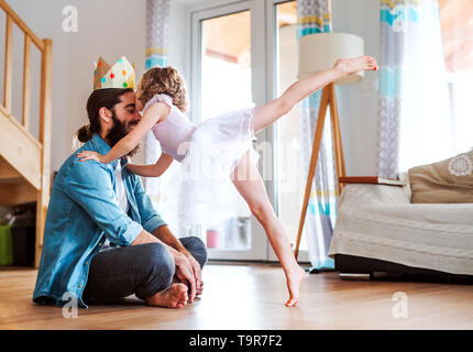 Seitenansicht der kleinen Mädchen mit einem Princess Crown und junger Vater zu Hause, spielen. Stockfoto