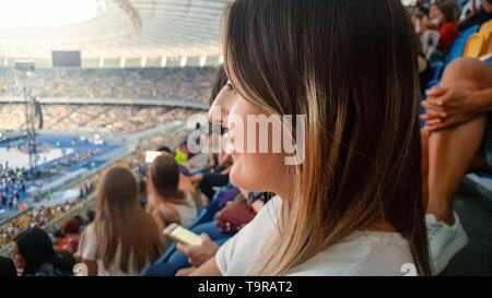 Closeup protrait von wunderschönen lächelnde junge Frau sitzt auf dem Stadion und Konzert in der Arena Stockfoto