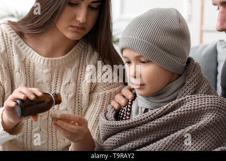 Die Mutter der Medizin zu ihrem Sohn krank mit Grippe zu Hause, Stockfoto