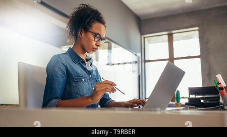 Junge geschäftsfrau an Ihrem Schreibtisch arbeiten. Weibliche Arbeiten am Laptop im Büro. Stockfoto