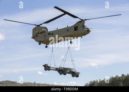 Ein U.S. Army CH-47 Chinook Hubschrauber, Bravo Company, 2.BATAILLON, 1 Combat Aviation Brigade, 1 Infanterie Division, führt eine Schlinge last betrieb mit Fallschirmjäger zu Charlie Company, 1.BATAILLON, 503Rd Infarnty Regiment, 173Rd Airborne Brigade, die während der Übung sofortige Reaktion am Vojarna Josip Jovic Airbase, Udbina, Kroatien, 16. Mai 2019. Übung sofortige Reaktion ist eine multinationale Übung von kroatischen Streitkräften geführt, der slowenischen Streitkräfte, und die US-Army in Europa. Die Logistik - fokussierte Übung ist entworfen, um zu prüfen, und die Fähigkeit, die Kräfte zu verbessern und Stockfoto