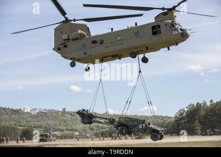 Ein U.S. Army CH-47 Chinook Hubschrauber, Bravo Company, 2.BATAILLON, 1 Combat Aviation Brigade, 1 Infanterie Division, führt eine Schlinge last betrieb mit Fallschirmjäger zu Charlie Company, 1.BATAILLON, 503Rd Infarnty Regiment, 173Rd Airborne Brigade, die während der Übung sofortige Reaktion am Vojarna Josip Jovic Airbase, Udbina, Kroatien, 16. Mai 2019. Übung sofortige Reaktion ist eine multinationale Übung von kroatischen Streitkräften geführt, der slowenischen Streitkräfte, und die US-Army in Europa. Die Logistik - fokussierte Übung ist entworfen, um zu prüfen, und die Fähigkeit, die Kräfte zu verbessern und Stockfoto