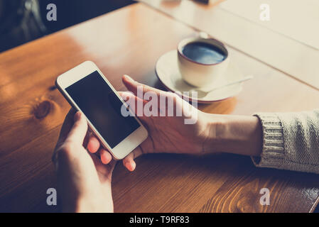 Frau mit Smartphone auf hölzernen Tisch im Café. Nahaufnahme mit sozialen Netzwerken Konzept Stockfoto