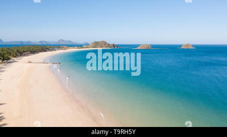 Luftaufnahme Insel mit tropischen Sandstrand und Palmen. Malajon Island, Philippinen, Palawan. touristischen Boote an der Küste tropischen Insel. Sommer und Reisen Urlaub. Strand und blaues Meer Wasser Stockfoto