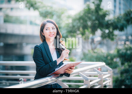 Portrait von Business Frau glücklich lächeln Holding Check liste auf Zwischenablage und Stift. Stockfoto