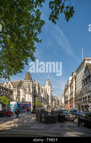 Blick auf Strand im Zentrum Londons mit den Royal Courts of Justice auf der linken Seite und grünen Bäumen, die an einem sonnigen Sommertag darüber hängen Stockfoto