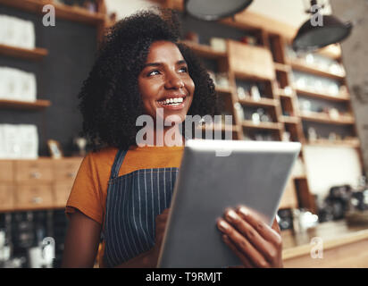 Eine afrikanische Frau Inhaber des Cafe Holding digital Tablet Stockfoto