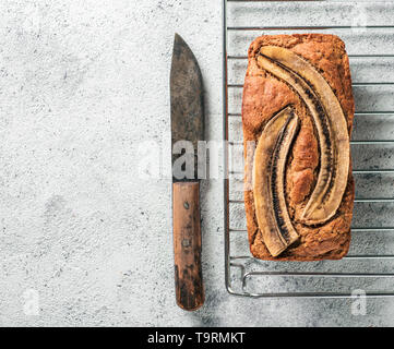 Butter, Zucker-freien Bananenbrot mit Hafermehl, weiche Quark und Honig. Blick von oben auf die volle Banane Brot auf grauzement Hintergrund. Kopieren Sie Platz. Ideen und Rezepte für gesunde Ernährung Frühstück Stockfoto