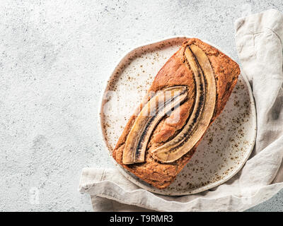 Butter, Zucker-freien Bananenbrot mit Hafermehl, weiche Quark und Honig. Blick von Oben auf die volle Banane Brot für das Handwerk die Platte über der grauen Hintergrund. Platz kopieren. Ideen und Rezepte für gesunde Ernährung Frühstück Stockfoto
