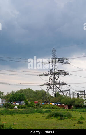 Blick über ein Feld von einem großen Strom pylon, Stromleitungen und Auto Schrottplatz in Familiars, Test Valley, Southampton, Hampshire, Südengland, Großbritannien Stockfoto