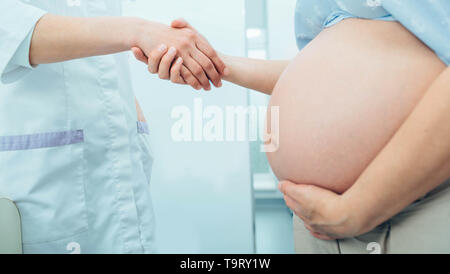 Schwangere Frau schütteln Doctor's Hand. Beratung Schwangerschaft Frau, pränatale Versorgung Stockfoto