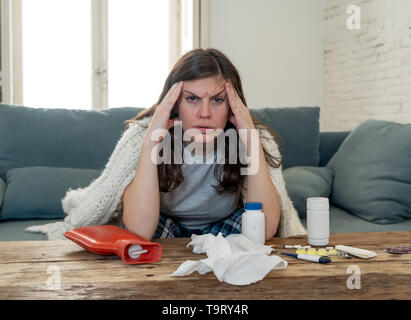 Kranke Frau in Schmerzen mit Kopfschmerzen Migräne und Temperatur Fühlen krank mit Grippe zu Hause auf dem Sofa sitzen. Lifestyle portrait. Health Care, Virus, Stockfoto