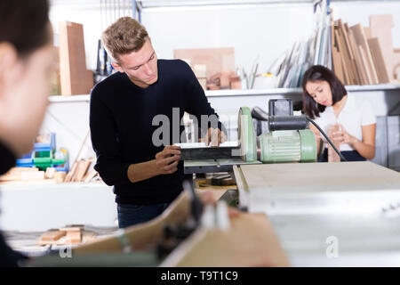 Der junge Architekt polieren Elemente der zukünftigen architektonischen Modell auf der Schleifmaschine in Design Studio Stockfoto