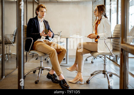 Junger Mann und Frau in einer geschäftlichen Besprechung während der Kaffeepause, sitzen zusammen im Tagungsraum. Stockfoto
