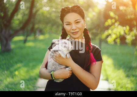 Hübsche Asiatin Hugging Bunny auf Sommer Natur Stockfoto