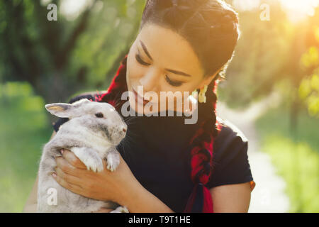 Hübsche Asiatin Hugging Bunny auf Sommer Natur Stockfoto