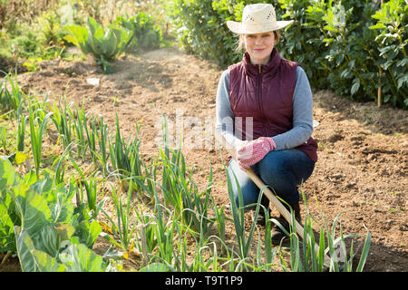 Portrait von Fröhliche Frau unter Porreepflanzen und Grüns auf Betten Stockfoto