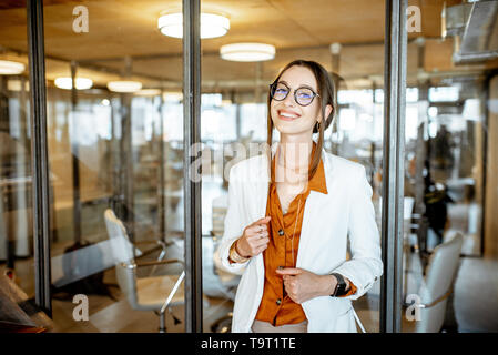 Portrait einer jungen und cherful Business stehende Frau mit Laptop im Büro Stockfoto