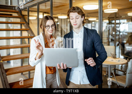 Young Business Mann und Frau ein Gespräch gemeinsam mit Laptop in der Halle des modernen Büro Stockfoto