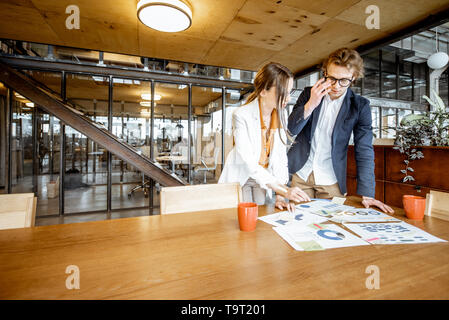 Young Business Mann und Frau Arbeiten an Dokumenten an den hölzernen Tisch im Büro oder Coworking Space Stockfoto