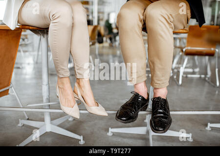 Elegante business Paar an der Bar sitzen, mit Blick auf ihre Beine unter dem Tisch Stockfoto