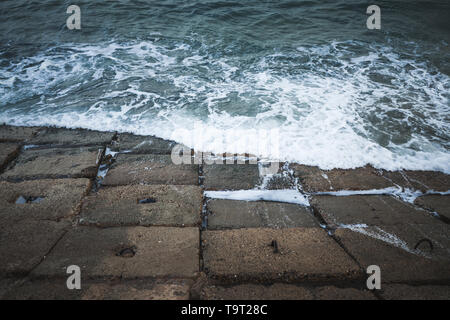 Dunkle konkrete seawall Blöcke mit stürmischen Wasser, Ägypten Alexandria, Ägypten Stockfoto