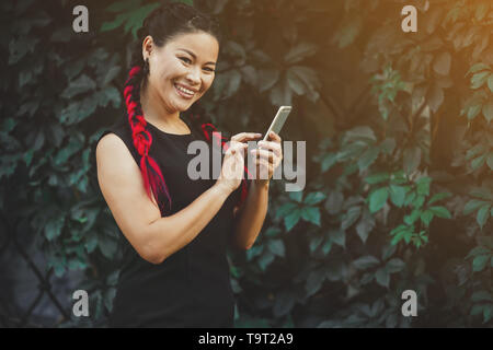 Wunderschöne reife asiatische weibliche Modell mit Smartphone Outdoor Stockfoto