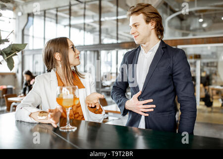 Geschäftsmann Flirten mit junge Frau sitzend mit Cocktail an der Bar Stockfoto