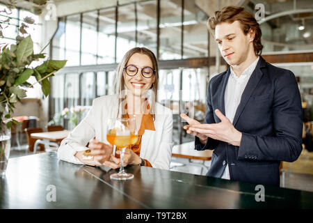 Geschäftsmann Flirten mit junge Frau sitzend mit Cocktail an der Bar Stockfoto