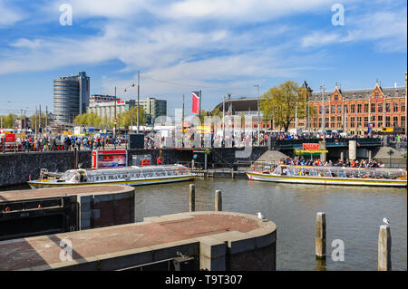 Amsterdam, Niederlande - 18 April 2019: Touristen sightseeng im Kanal Boote in der Nähe des Hauptbahnhofs von Amsterdam. Stockfoto