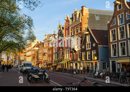 Amsterdam, Niederlande - 18 April 2019: Spirngtime Blick auf die tanzenden Häuser der Altstadt im Zentrum von Amsterdam, in warmen Sonnenstrahlen Sonnenuntergang Stockfoto