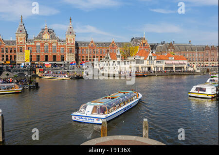 Amsterdam, Niederlande - 18 April 2019: Touristen sightseeng im Kanal Boote neben dem Hauptbahnhof von Amsterdam. Stockfoto