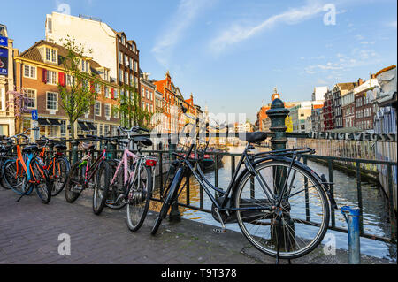 Amsterdam, Niederlande - 18 April 2019: Verschiedene Fahrräder an Brücke Geländer im historischen Zentrum von Amsterdam gesperrt am Abend geparkt Stockfoto