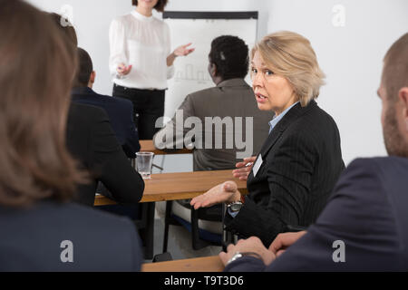Unzufriedenheit senior Frau drehen an andere Teilnehmer während der Präsentation Stockfoto