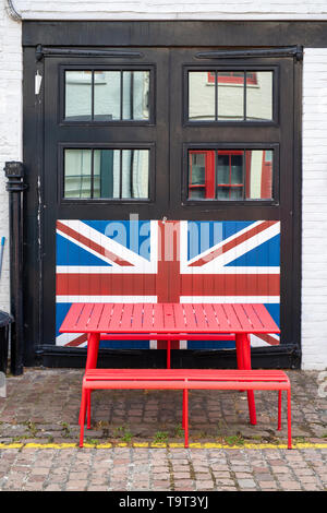 Roter Tisch vor einem Löwen Jack auf schwarz Garagentore in Cranley Mews gemalt, South Kensington, SW7, London. England Stockfoto