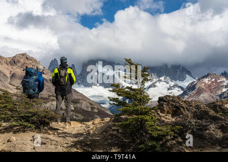 Zwei Wanderer über Mount Fitz Roy in den Wolken in Los Glaciares Nationalpark in der Nähe von El Chalten, Argentinien. Weltkulturerbe der UNESCO in Patagonien Stockfoto