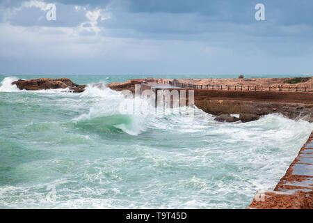 Küstenlandschaft mit Wellen auf stürmischer See Wasser unter Dunkelblau bewölkten Himmel. Stadt Alexandria, Ägypten Stockfoto