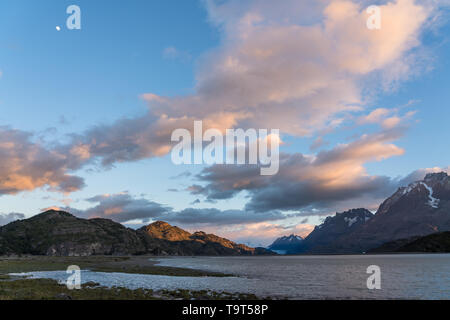 Der Mond und die farbenfrohen Sonnenaufgang Wolken über dem Lago Grey, Torres del Paine National Park, ein UNESCO-Biosphärenreservat in Chile Patagonien Regi Stockfoto