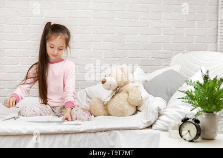 Süße kleine Mädchen Zeichnen von Bildern beim liegen auf dem Bett. Kind malen zu Hause Stockfoto