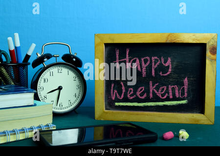 Happy Weekend! Auf dem Hintergrund der Arbeitstisch mit Bürobedarf. Business Konzept Planung auf blauem Hintergrund Stockfoto