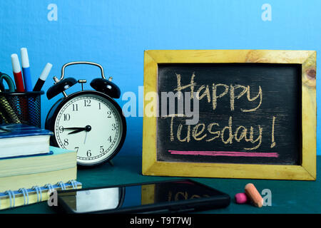 Happy Dienstag! Auf dem Hintergrund der Arbeitstisch mit Bürobedarf. Business Konzept Planung auf blauem Hintergrund Stockfoto