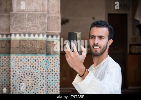 Junge muslimische Mann in traditioneller Kleidung lächelnd und unter selfie mit Handy Stockfoto